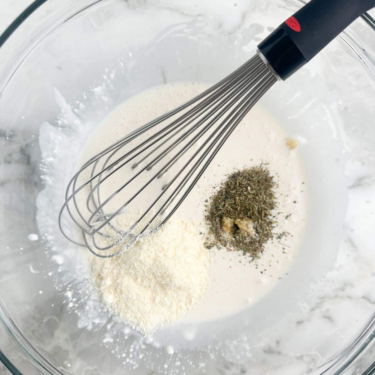 Bowl of dressing with grated cheese and seasonings. 