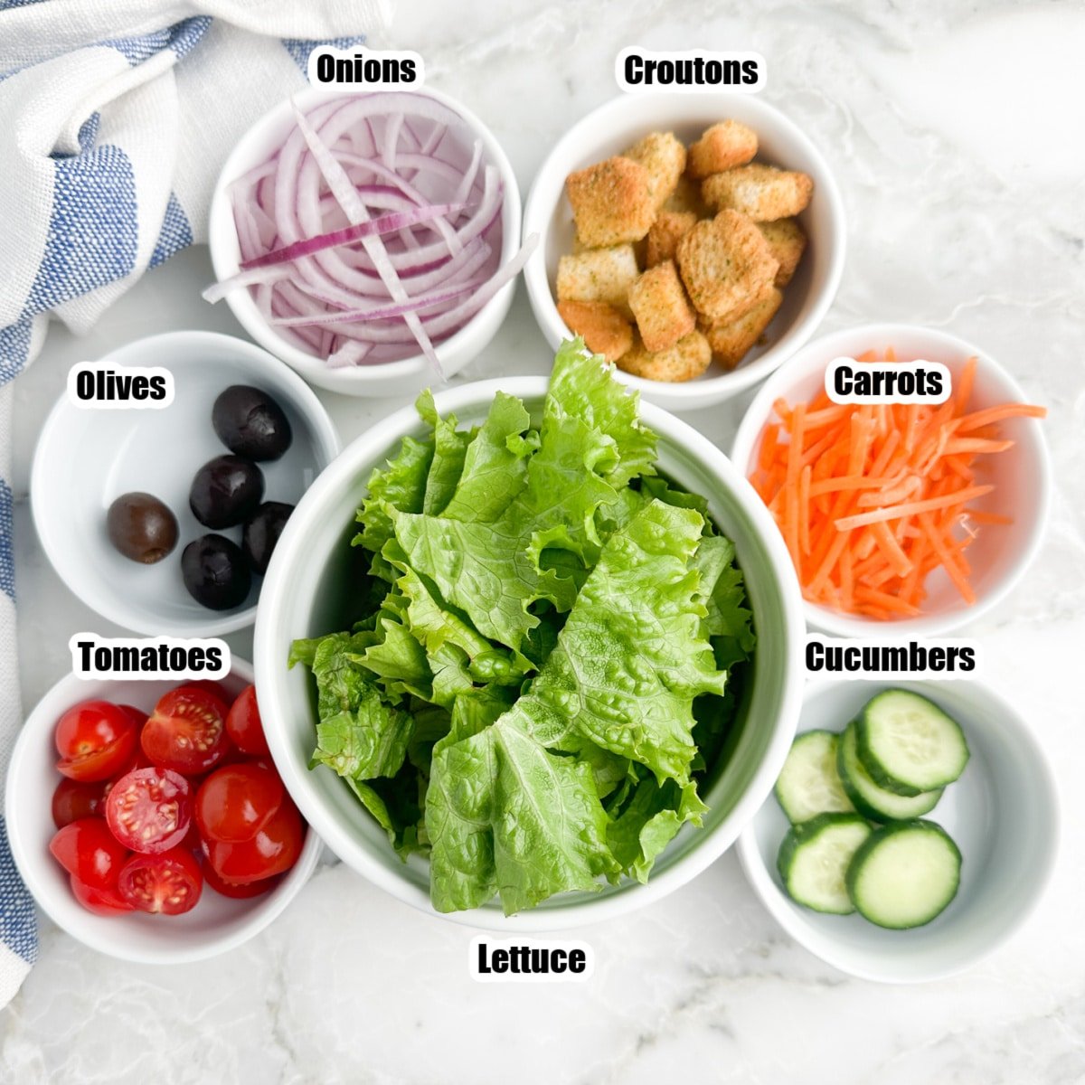 Bowl of lettuce, onions, croutons, carrots, cucumbers, tomatoes, and olives. 