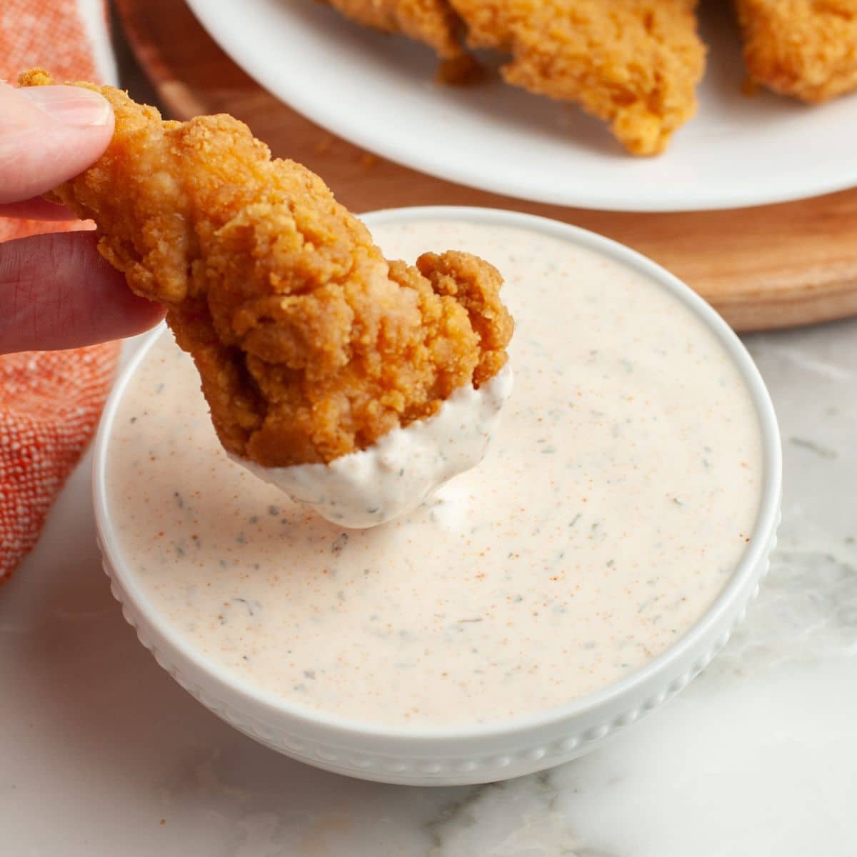 Bowl of sauce with chicken tender.