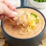 Bowl of bean dip with chip dipping the dip.