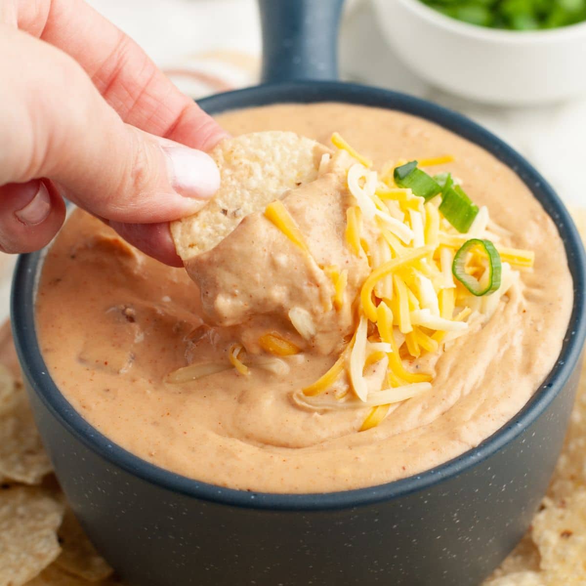 Bowl of bean dip with a chip dipping in the bowl.