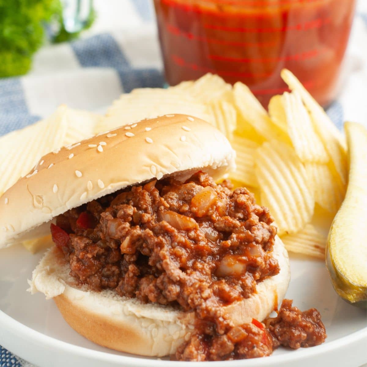 Sloppy joe sandwich on a plate with potato chips. 