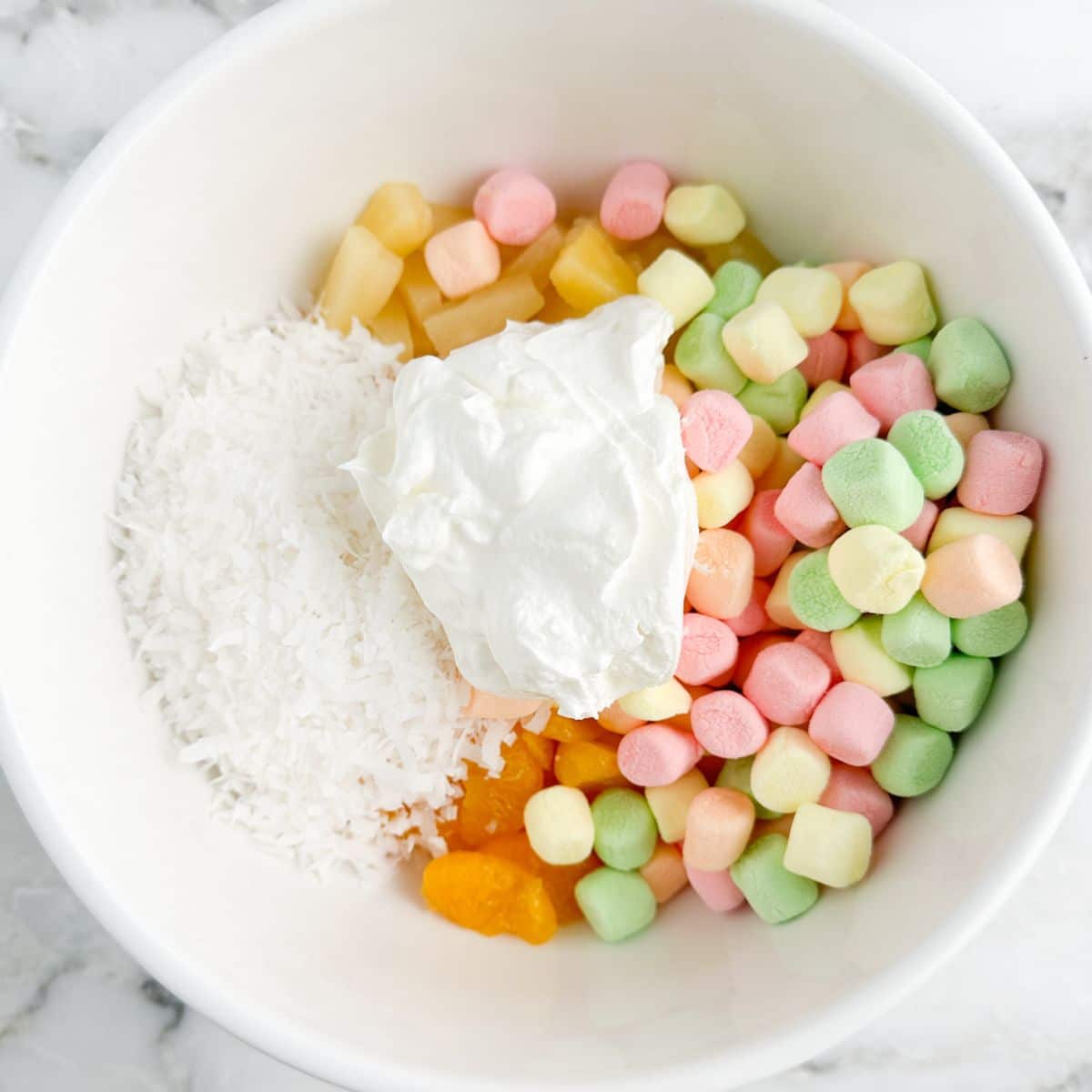 Bowl with shredded coconut, sour cream, and colorful marshmallows. 
