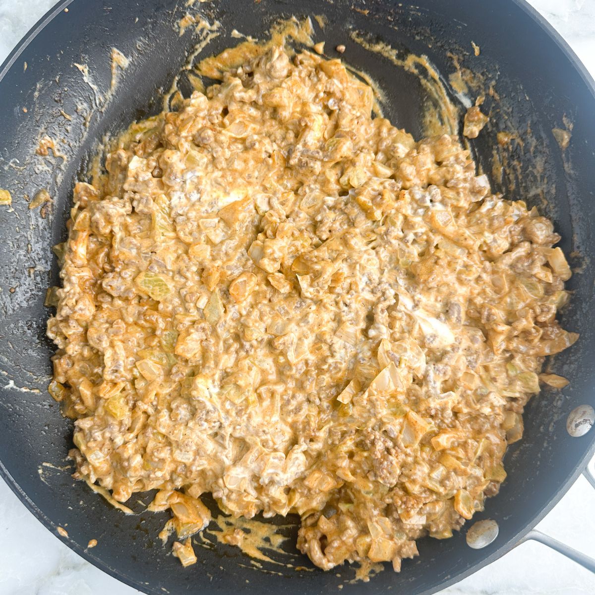 Skillet with ground beef and melted cream cheese.