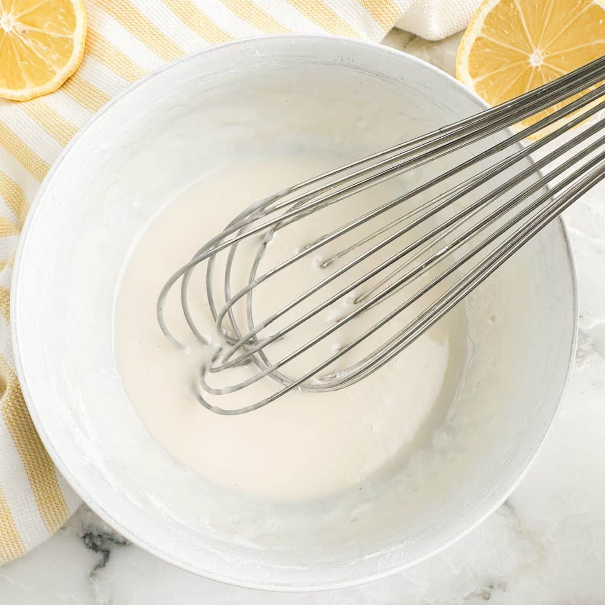 Bowl of lemon glaze with a whisk. 