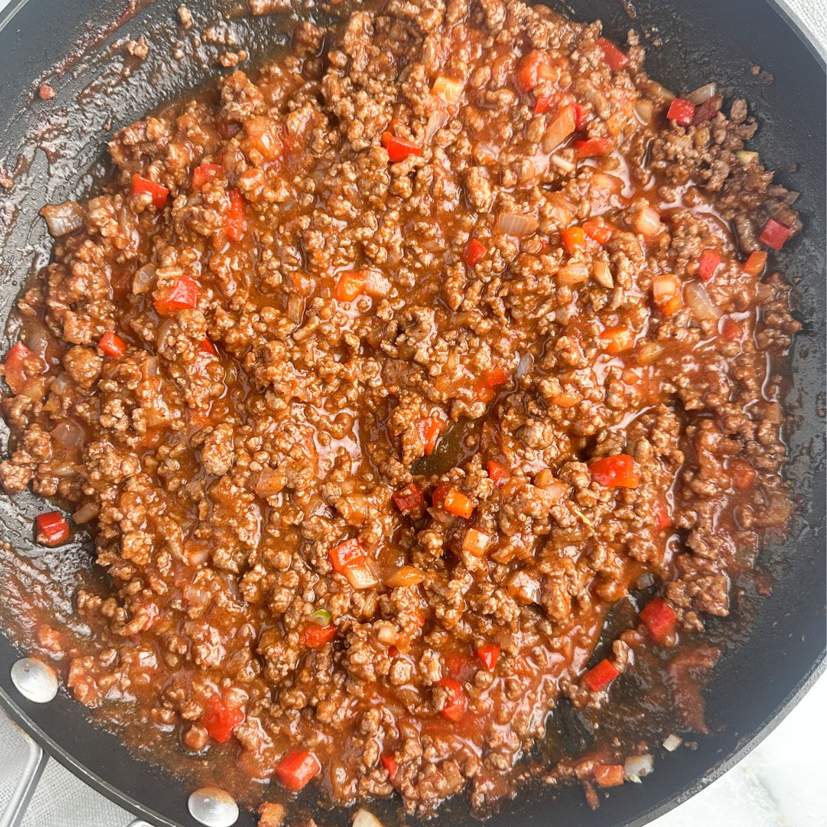 Skillet with cooked ground beef in tomato sauce. 