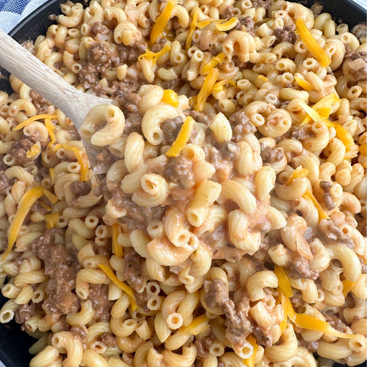 Wooden spoon with macaroni and cheese with ground beef. 