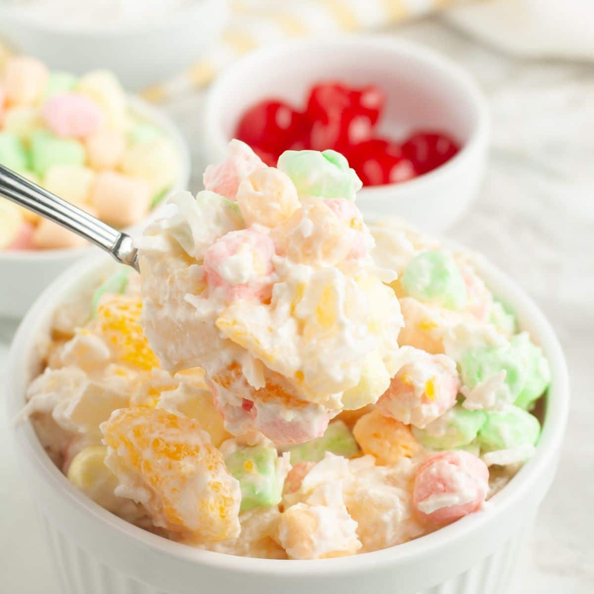 Bowl of fruit salad with a spoon scooping up the fruit salad. 