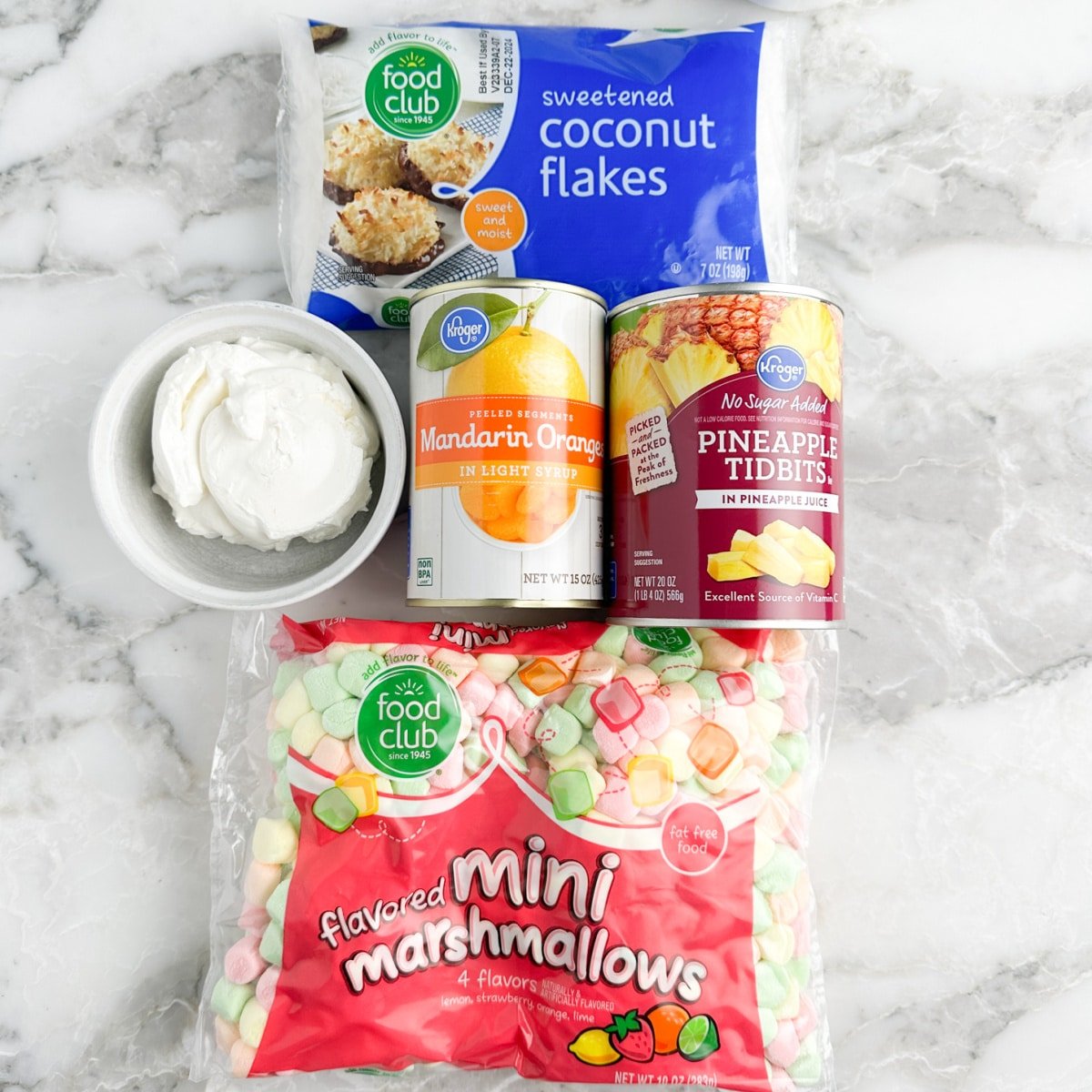 Bag of sweetened coconut, bowl of sour cream, cans of mandarin oranges, pineapple, and bag of colorful marshmallows. 
