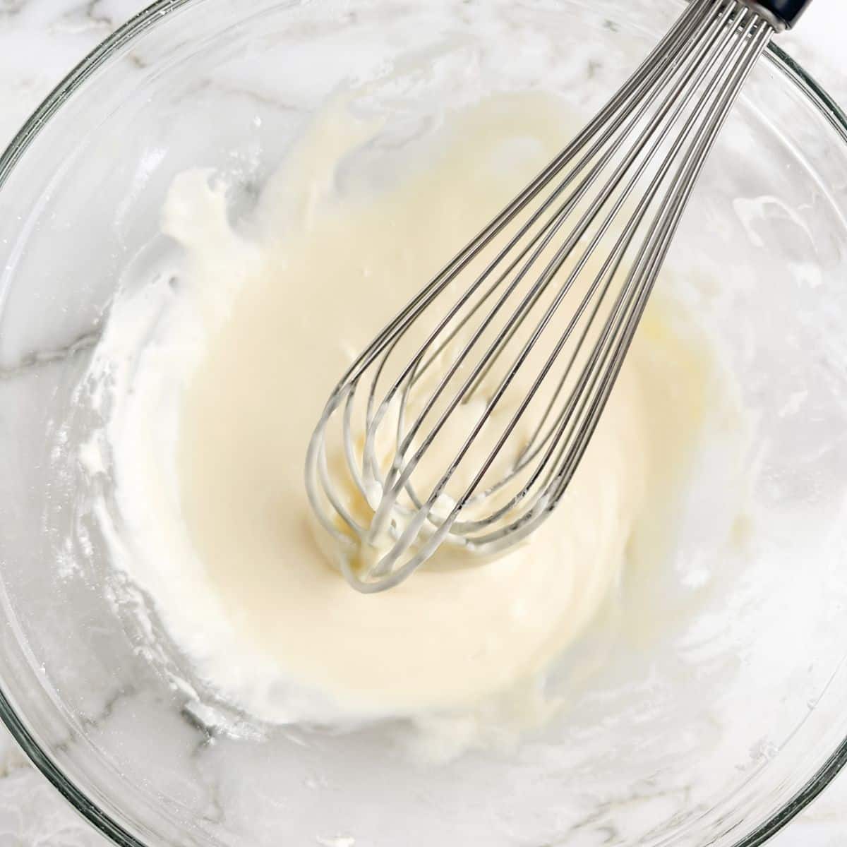 Bowl with orange icing and whisk. 