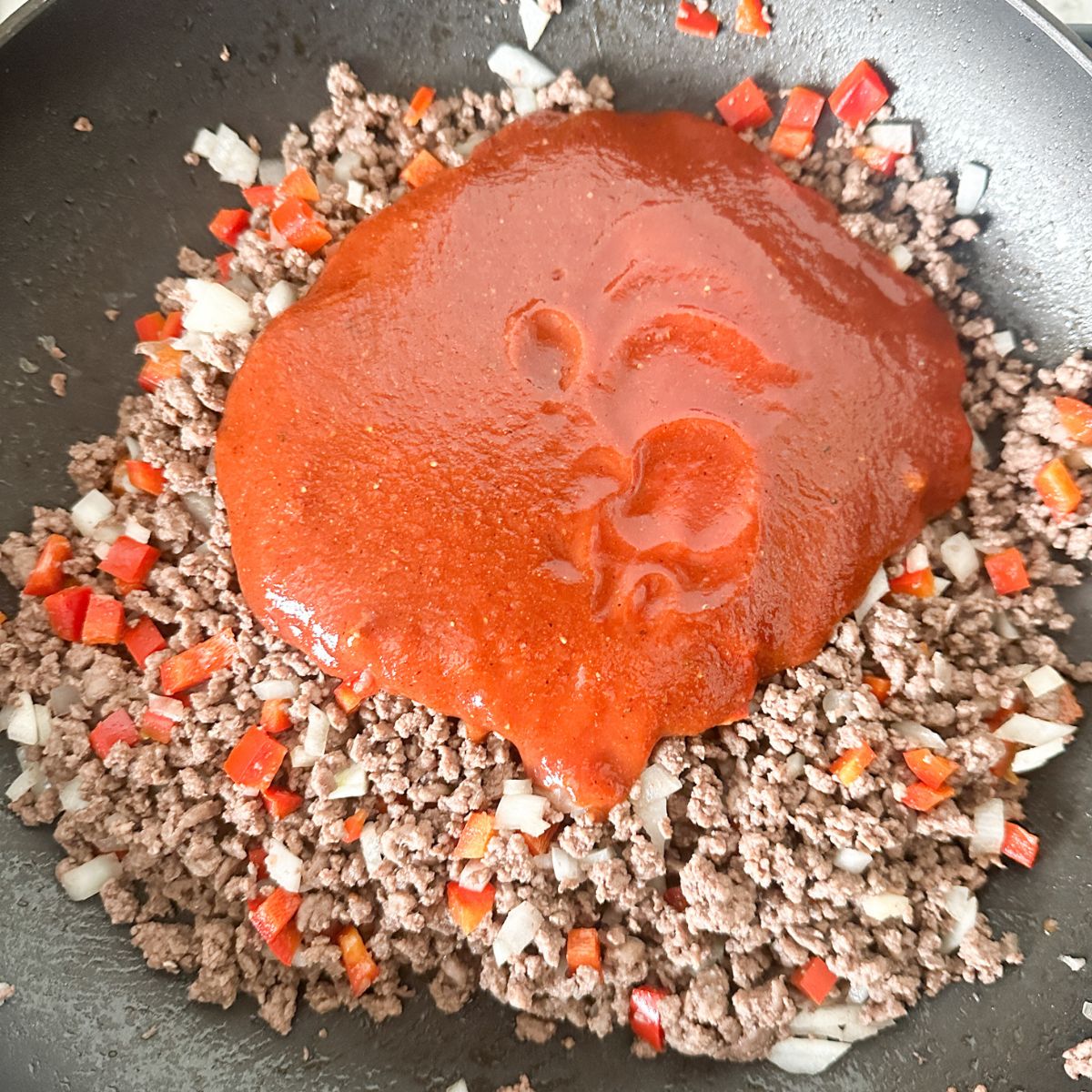 Skillet with ground beef and red sauce. 