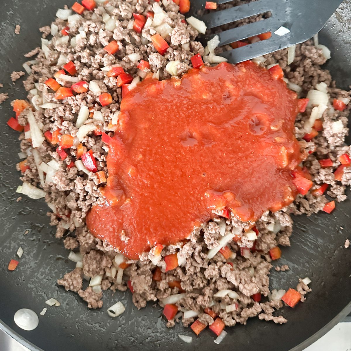 Skillet with ground beef and tomato sauce.