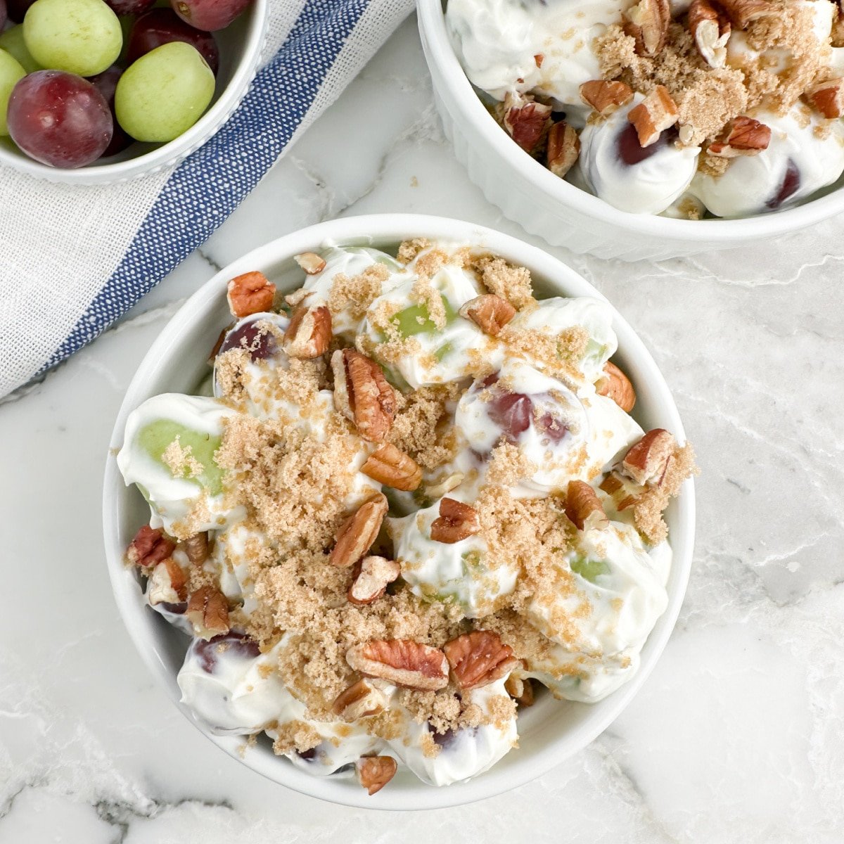 Bowl of green and red grape salad topped with brown sugar. 