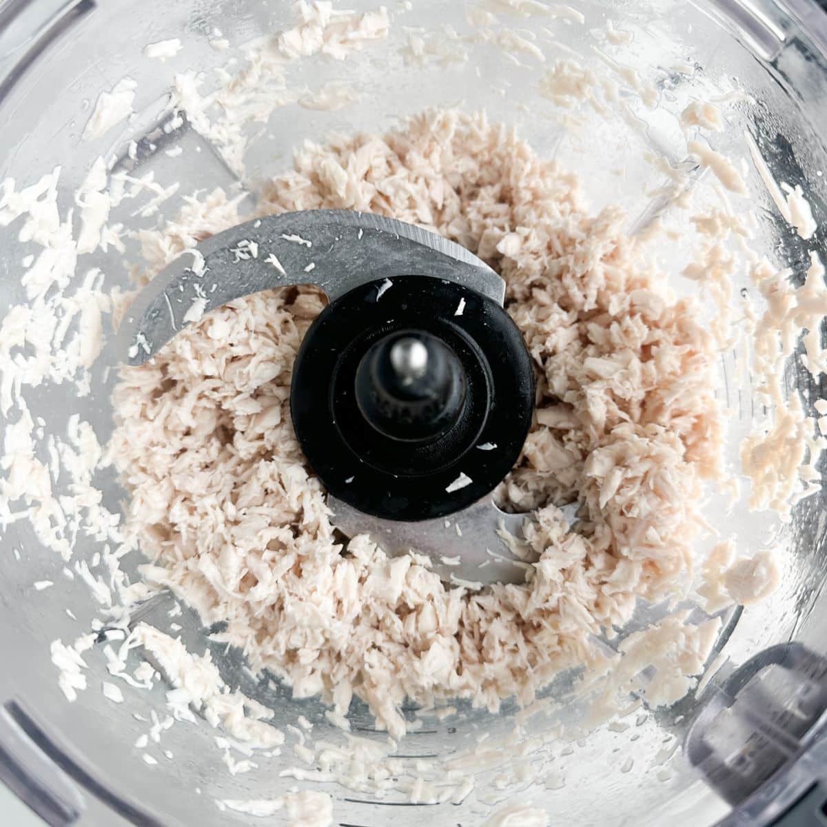 Food processor with chopped chicken.