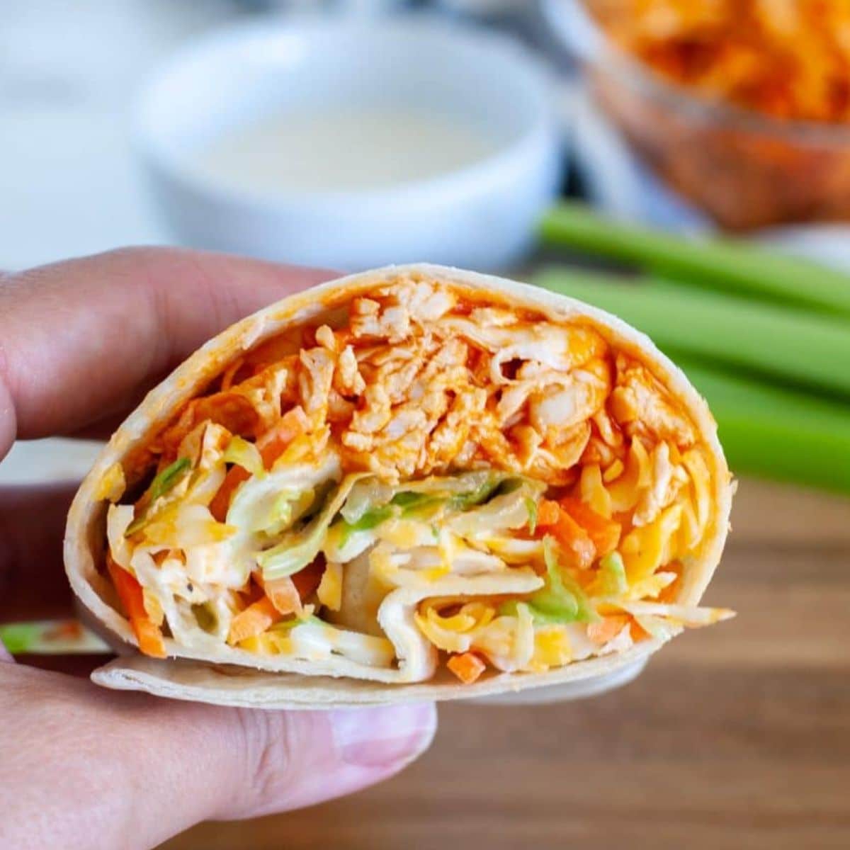 Hand holding buffalo chicken wrap. 