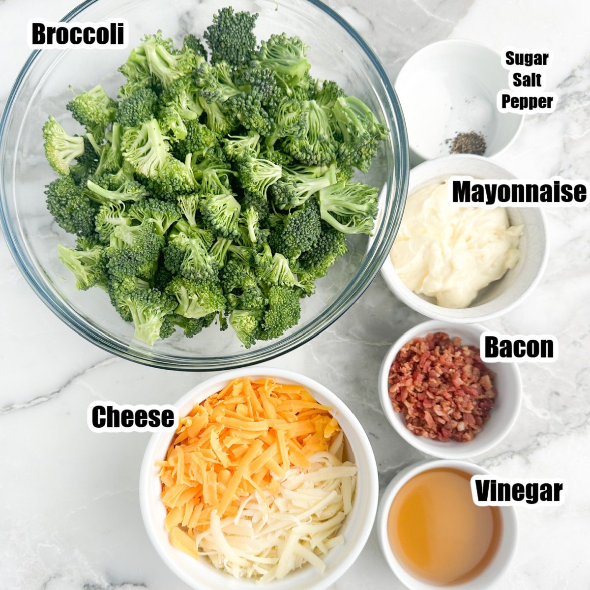 Bowl of broccoli florets, cheese, bacon bits, mayonnaise, and vinegar.