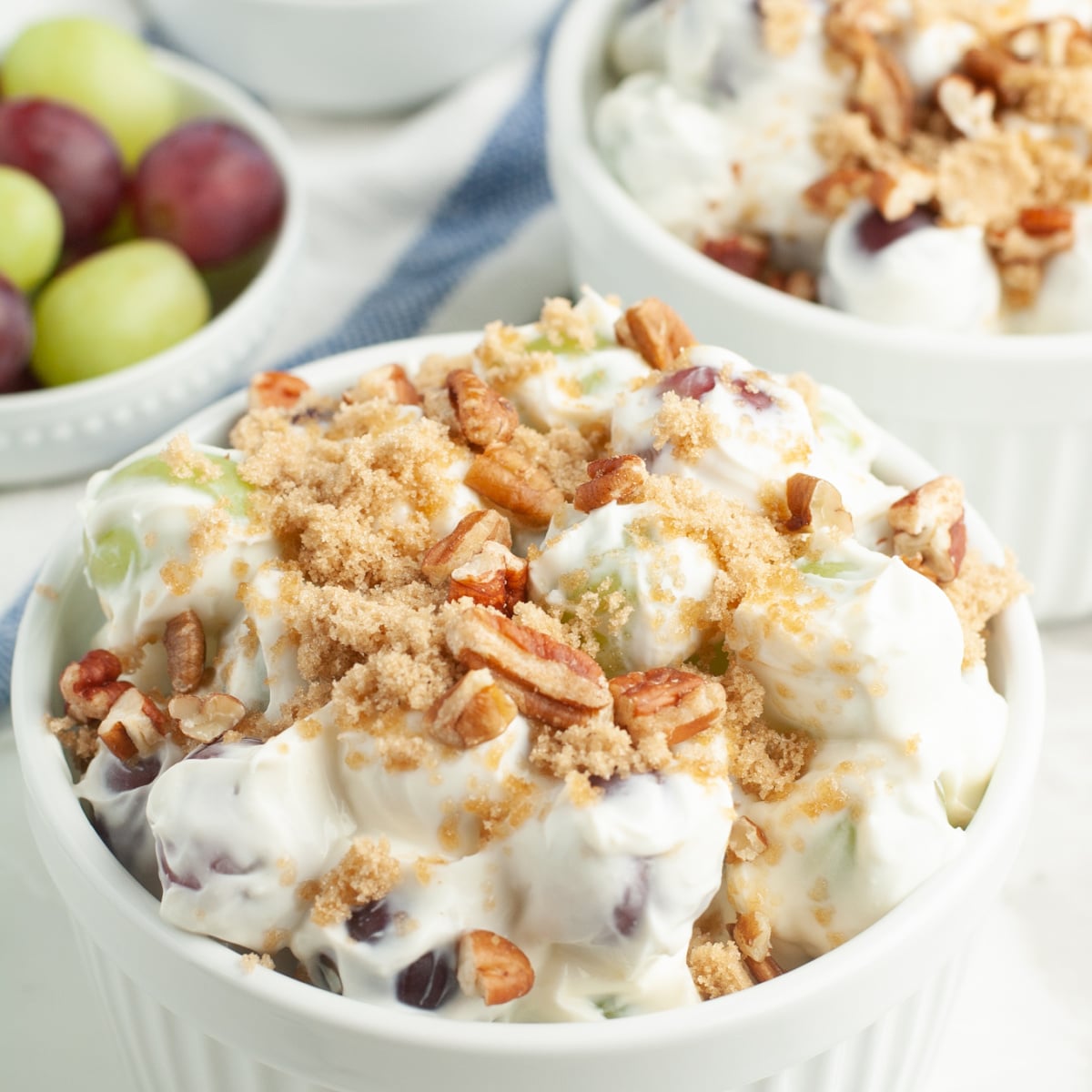 Bowl of grape salad topped with brown sugar and pecans. 