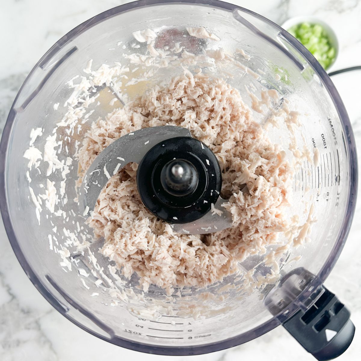 Food processor with shredded chicken.