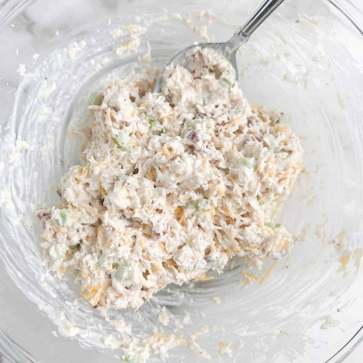 Bowl with chicken salad and a spoon.