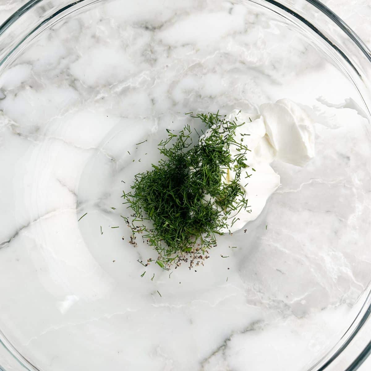 Bowl with mayonnaise, fresh dill, and seasonings.