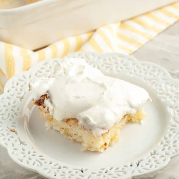 Piece of pineapple cake on a plate with whipped topping.