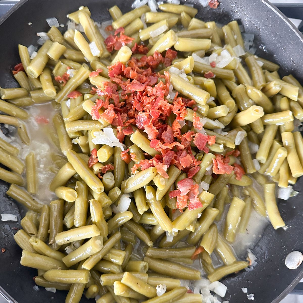 Skillet with green beans, and bacon bits.