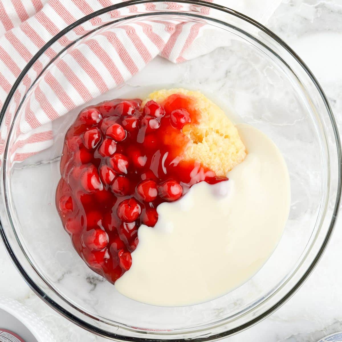 Bowl with cherry pie filling, crushed pineapple, and sweetened condensed milk. 