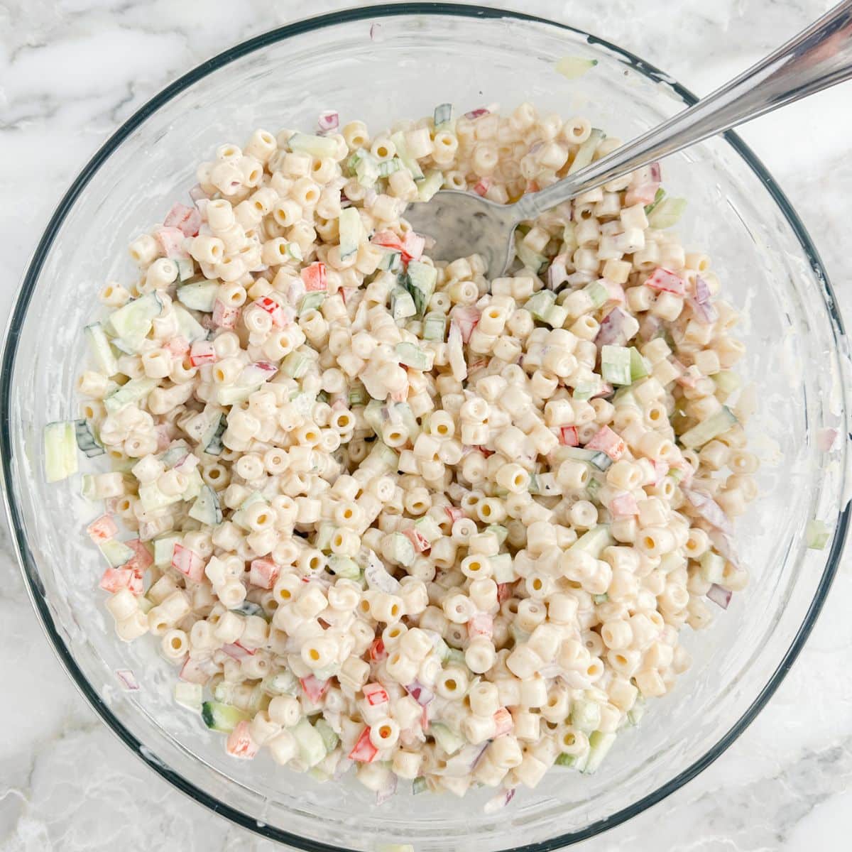 Bowl of creamy pasta salad with a spoon.