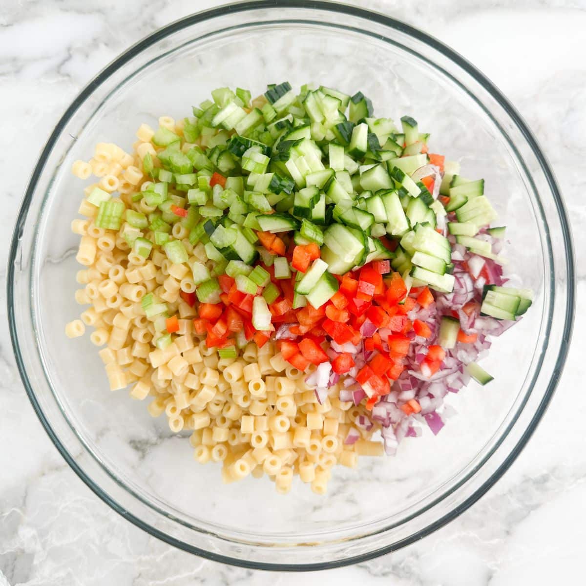 Bowl with pasta and chopped vegetables. 