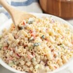 Creamy pasta salad with a wooden spoon.