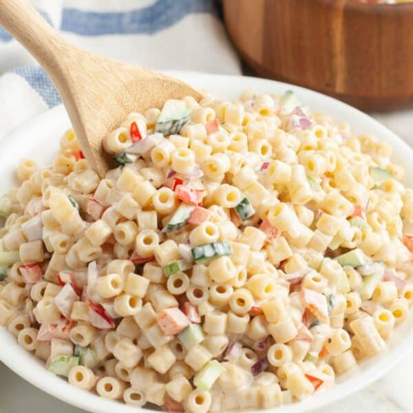Creamy pasta salad with a wooden spoon.