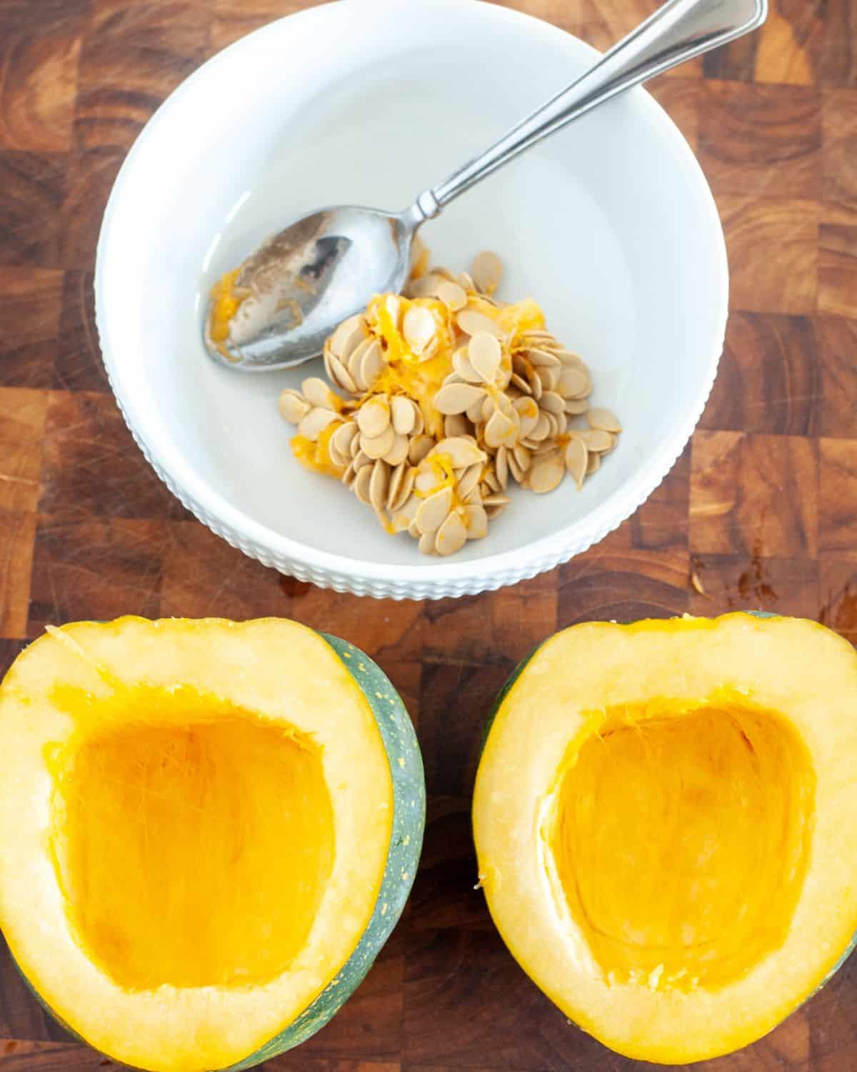 Halved acorn squash with a bowl of seeds. 