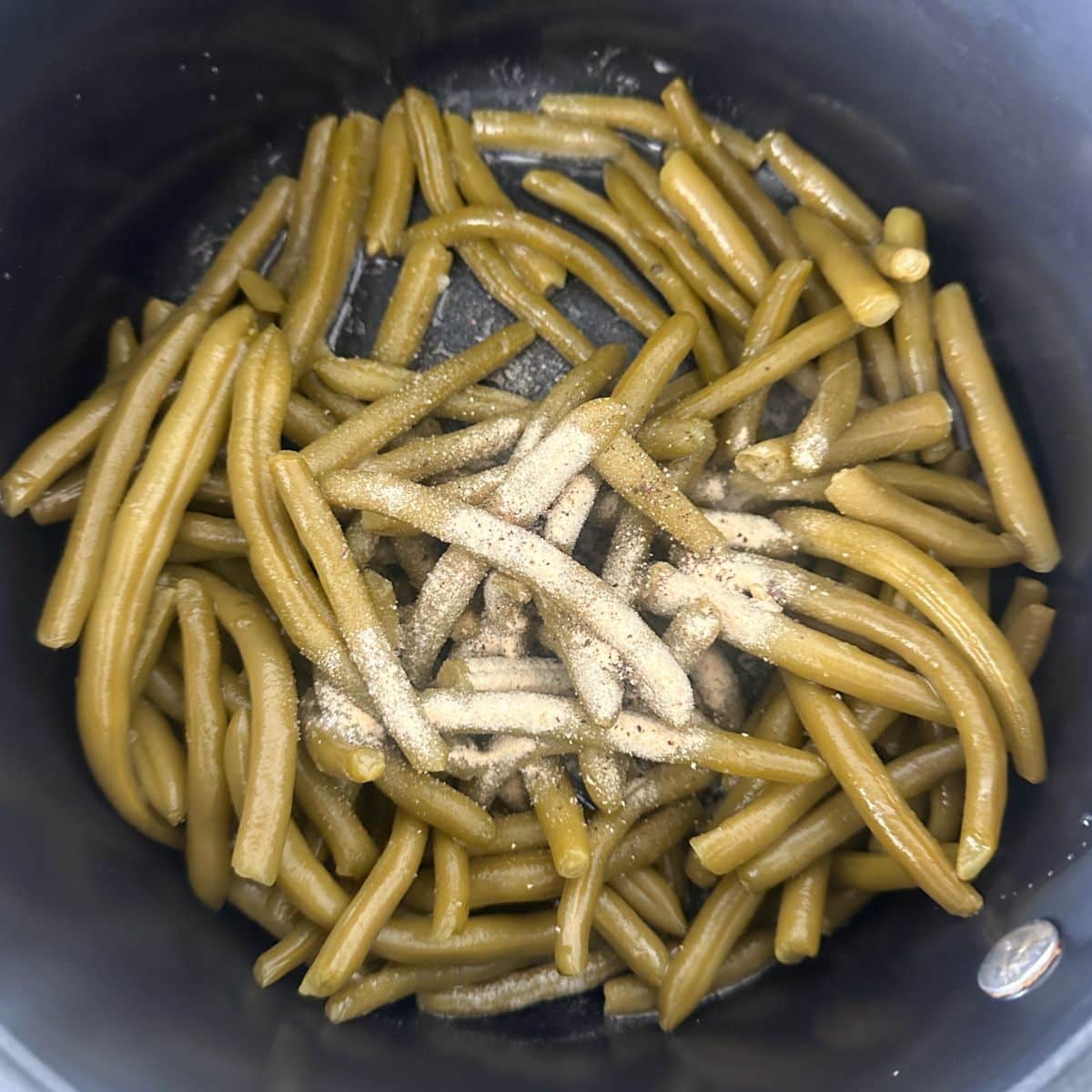 Green beans in a pot with seasoning.