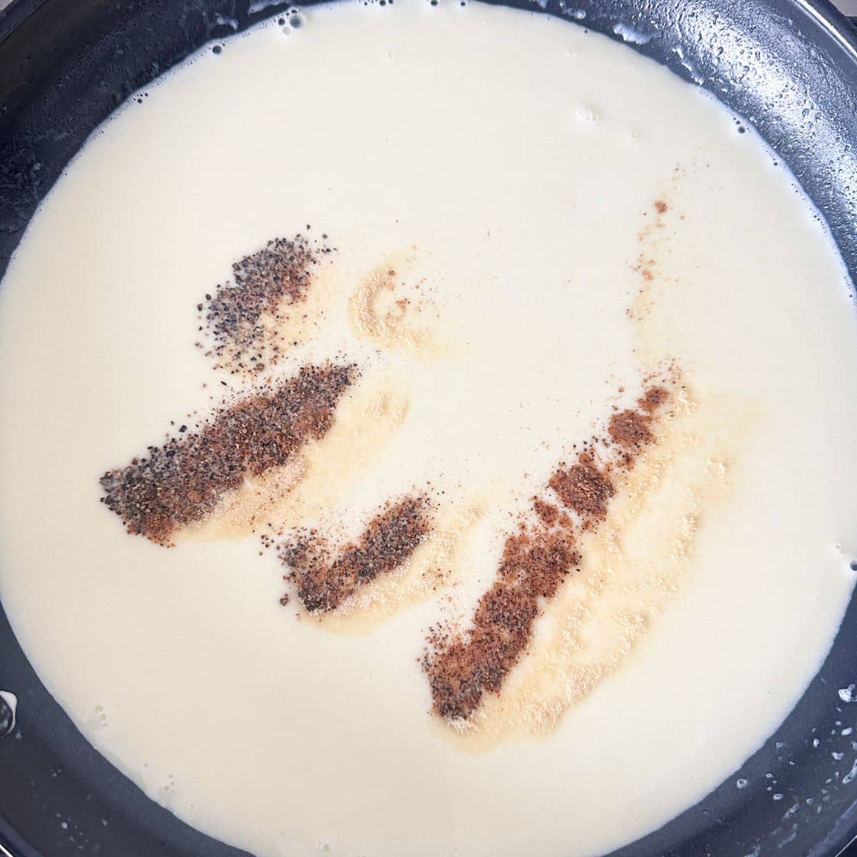 Skillet with alfredo sauce and seasonings.