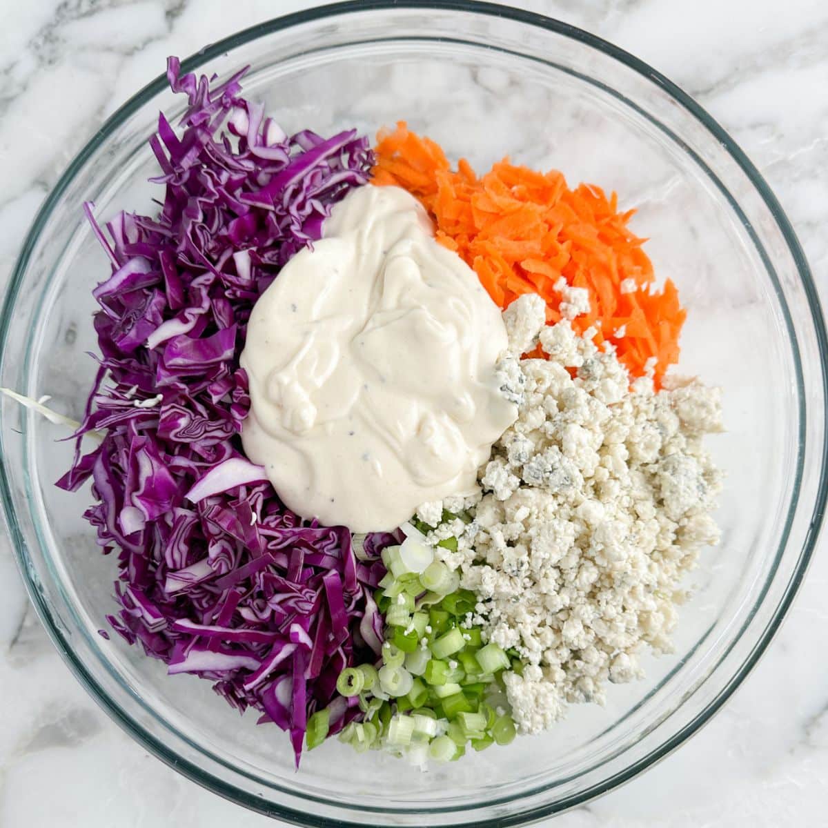 Bowl of cabbage, carrots, blue cheese, and dressing.