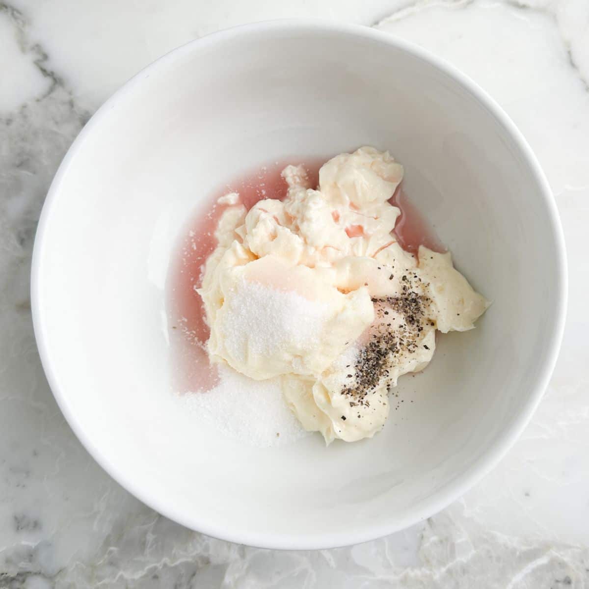 Bowl with mayonnaise, vinegar, salt, and pepper.