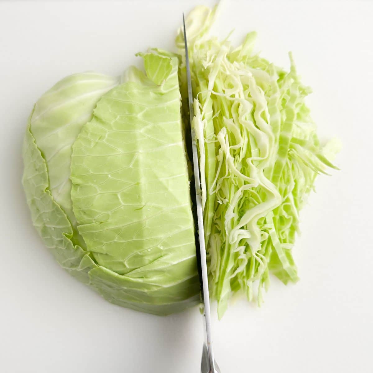 Knife cutting into a cabbage.
