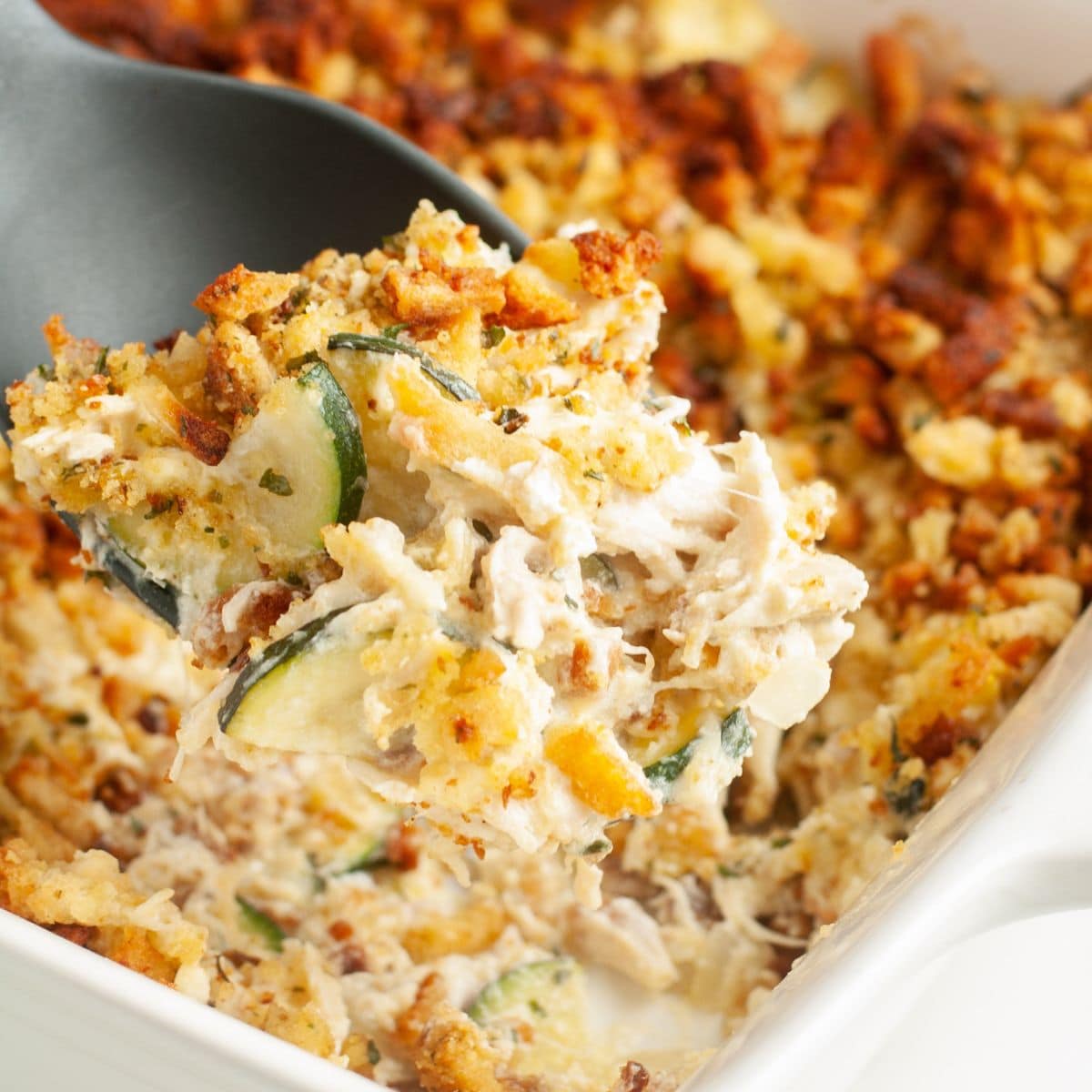 Spoon scooping out chicken zucchini squash casserole.