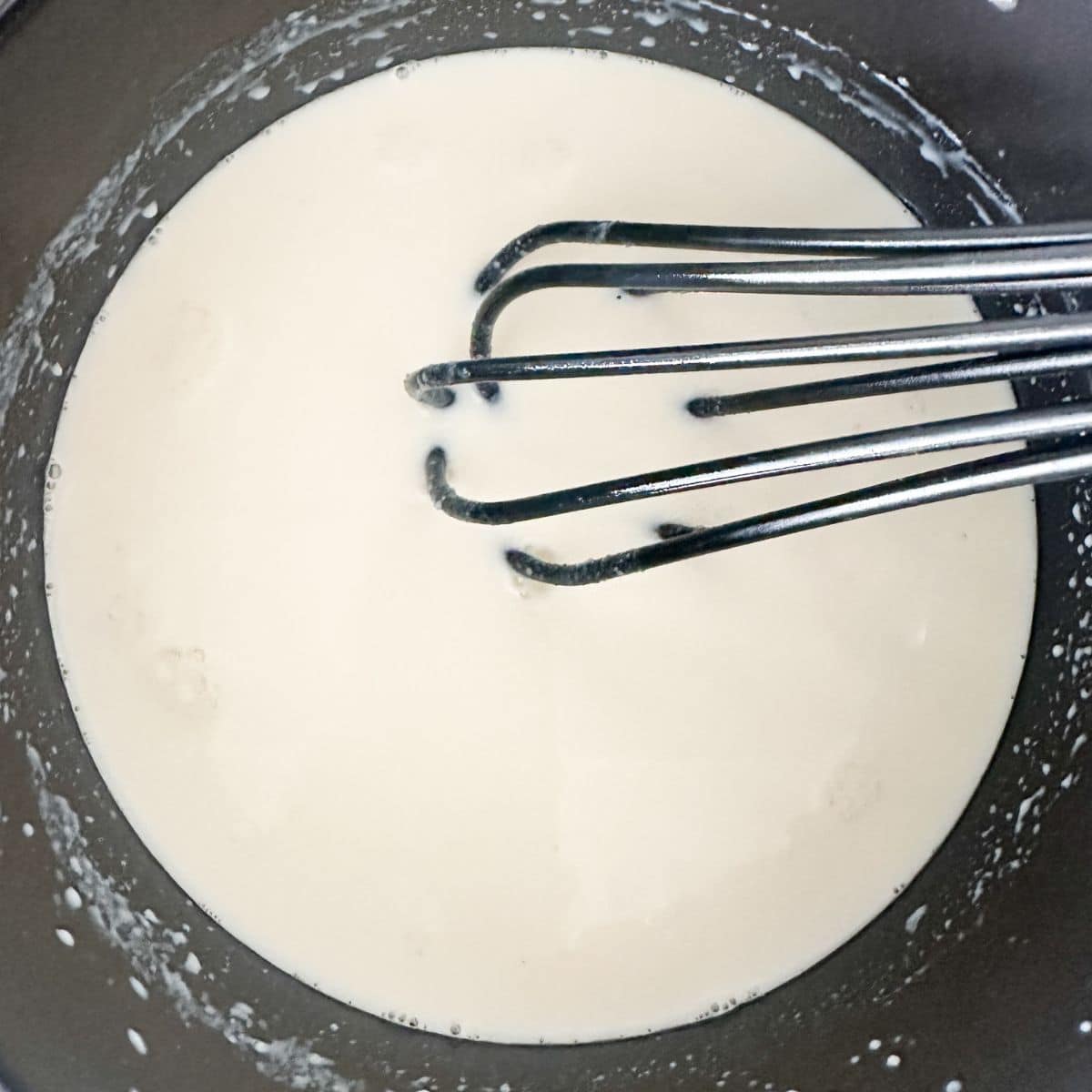 Saucepan with a whisk and gravy.