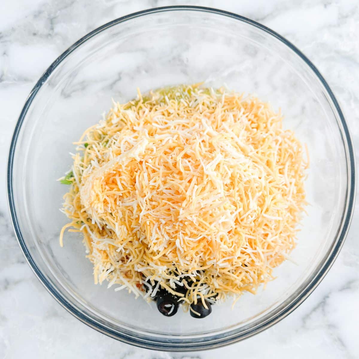 Bowl with shredded cheese, olives, and diced tomatoes.