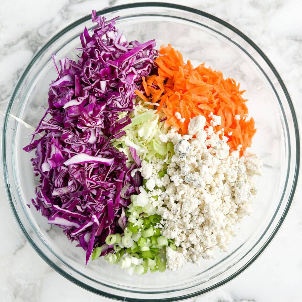 Bowl with red and green cabbage, carrots, and blue cheese crumbles.