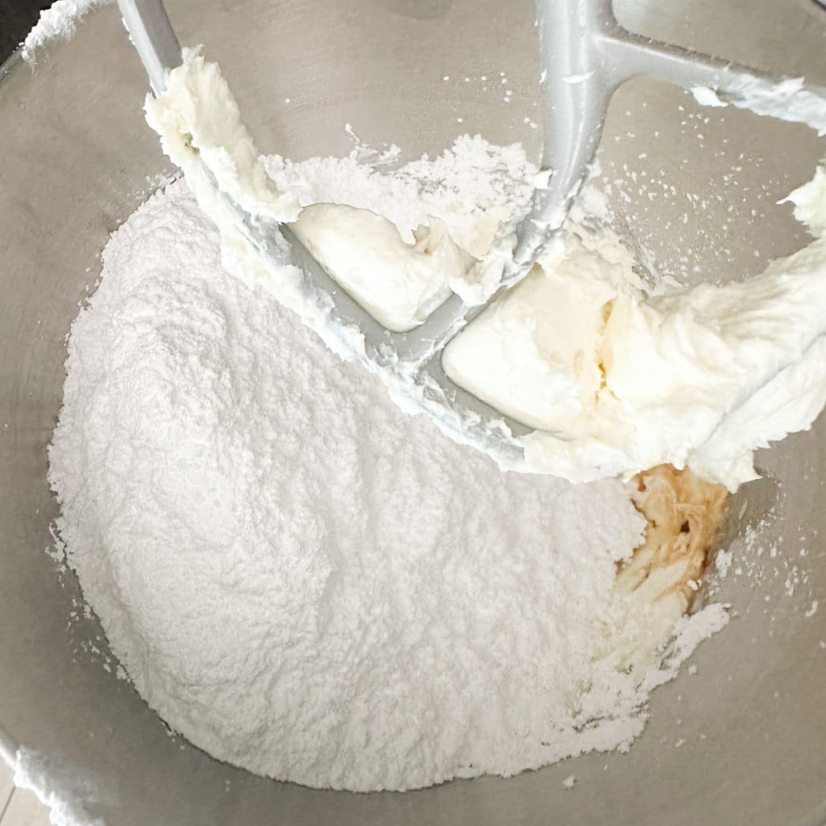 Mixing bowl with powdered sugar and cream cheese.