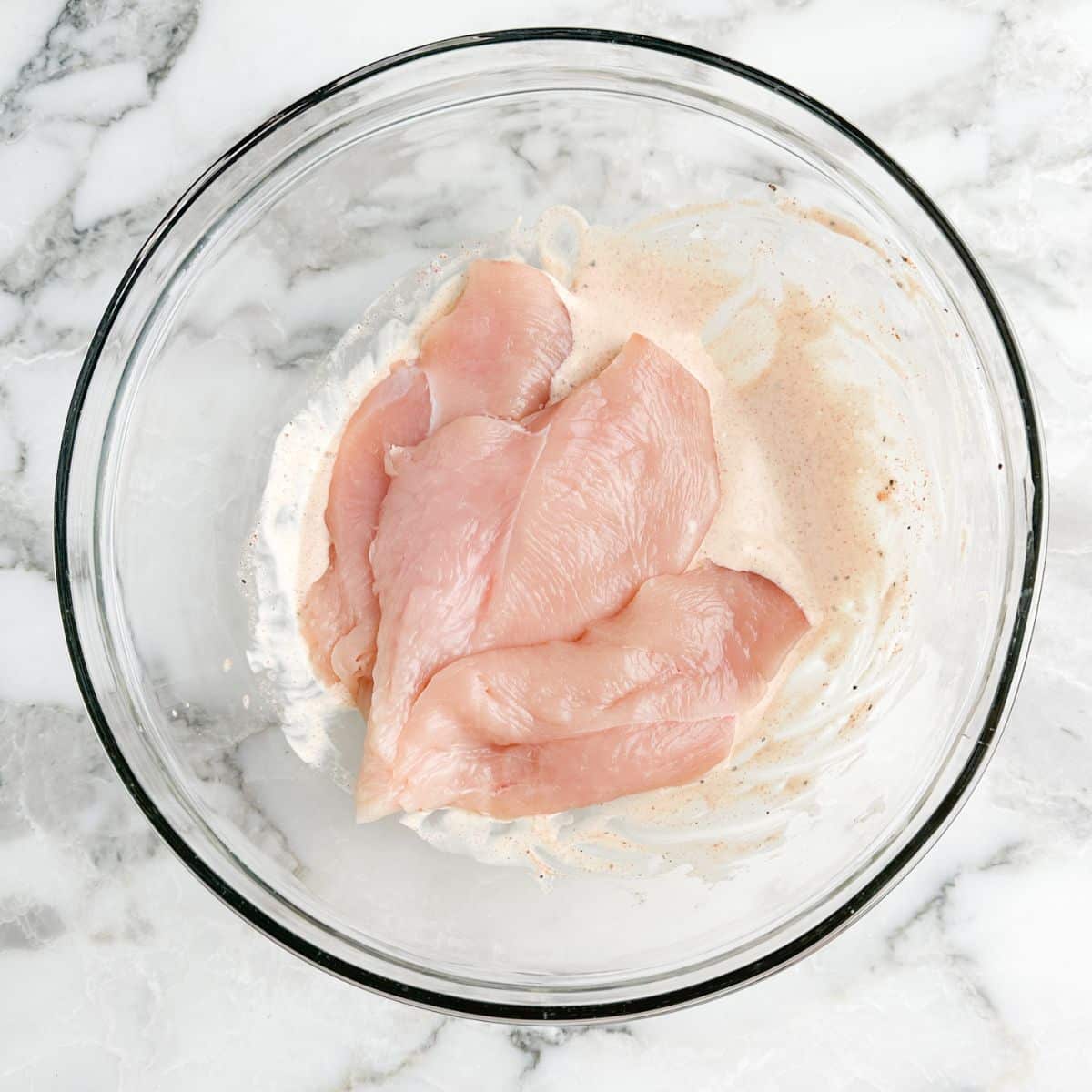 Bowl of mayo marinade with chicken.