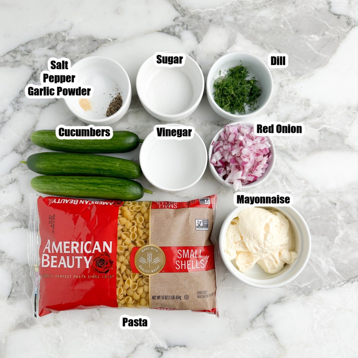 Cucumber, bag of pasta, bowl of mayonnaise, onions, dill, sugar, vinegar, and seasonings.