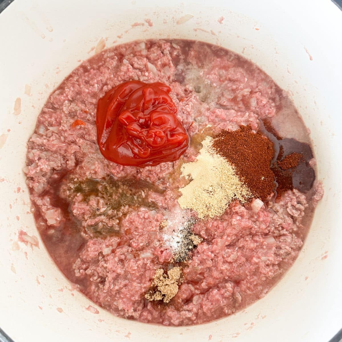 Pot with ground beef, ketchup, and spices.