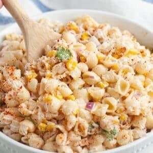 Bowl of elote pasta salad with a wooden spoon.