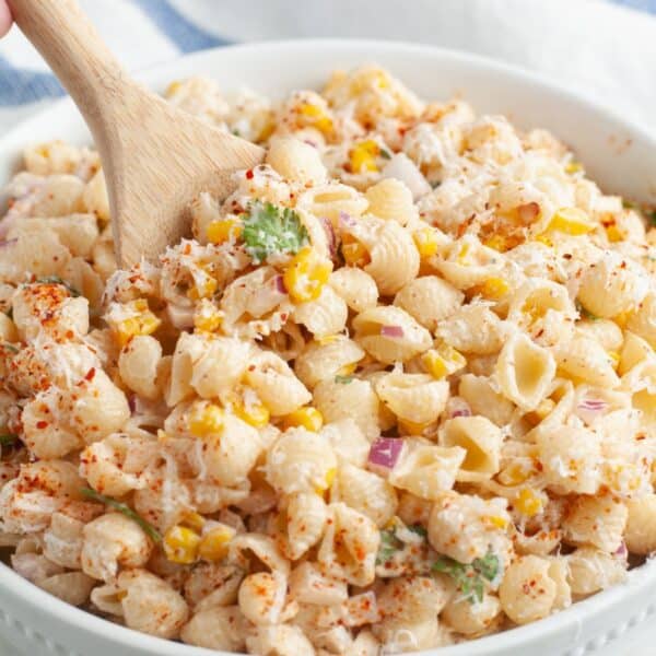 Bowl of elote pasta salad with a wooden spoon.
