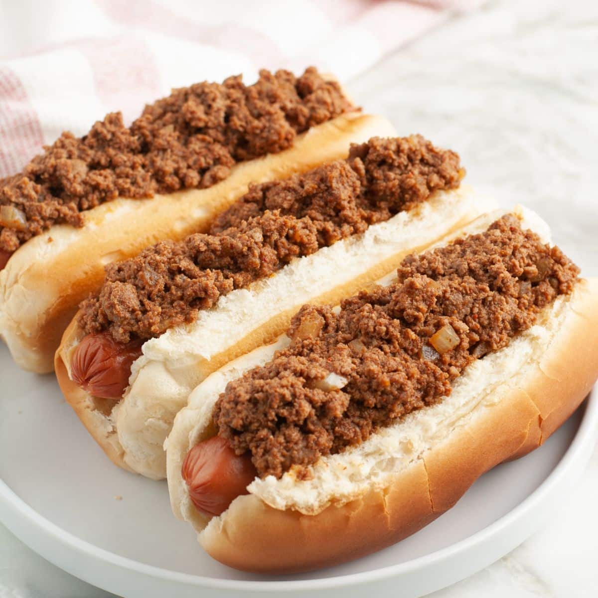 Plate of three chili dogs.