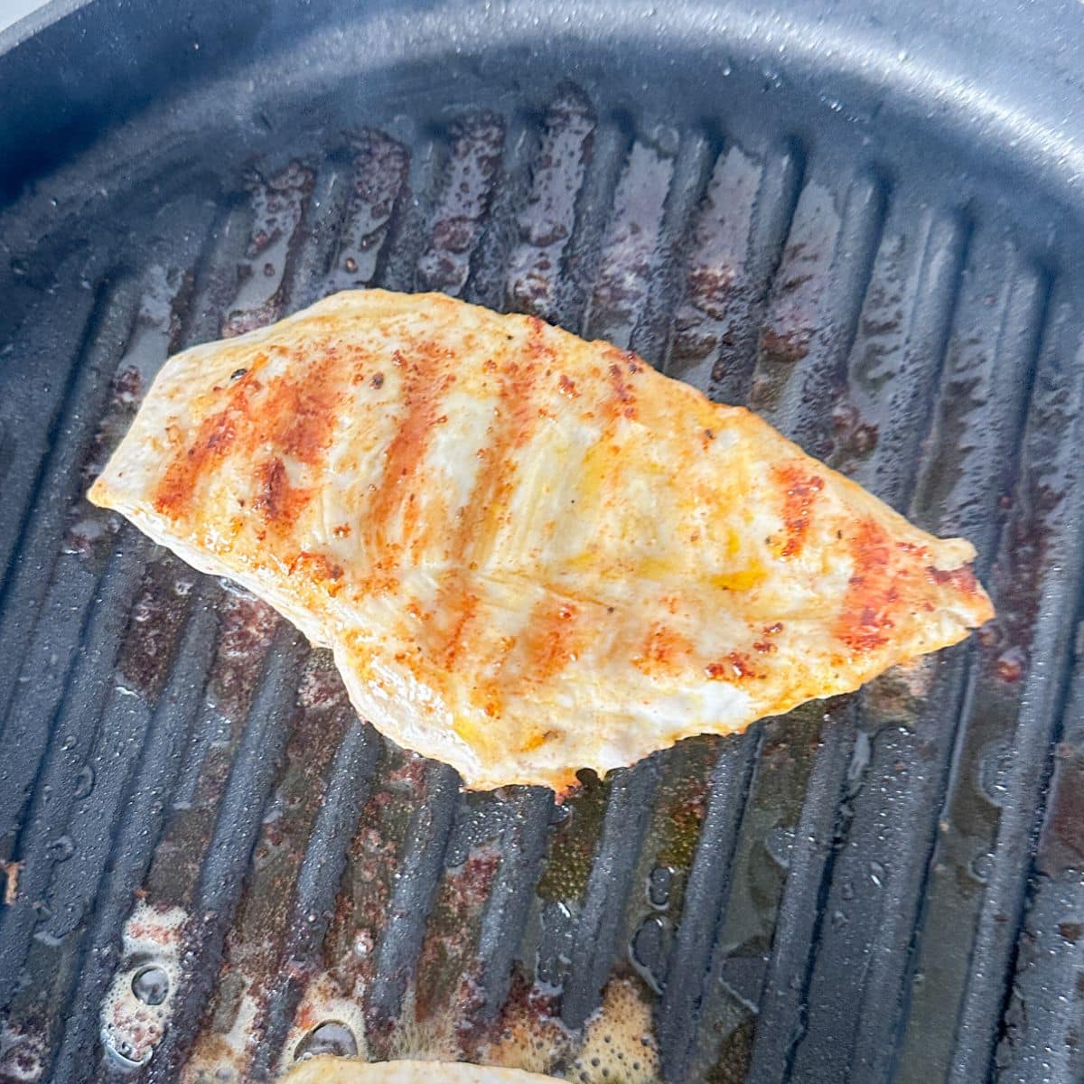 Grill pan with grilled chicken breast.