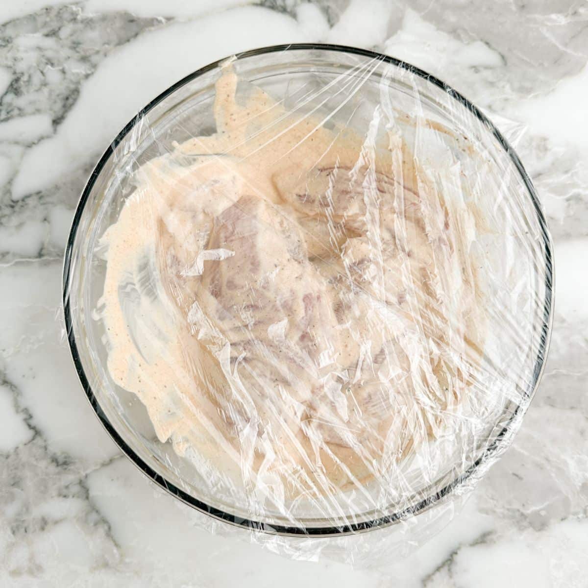 Bowl of uncooked chicken in a marinade.